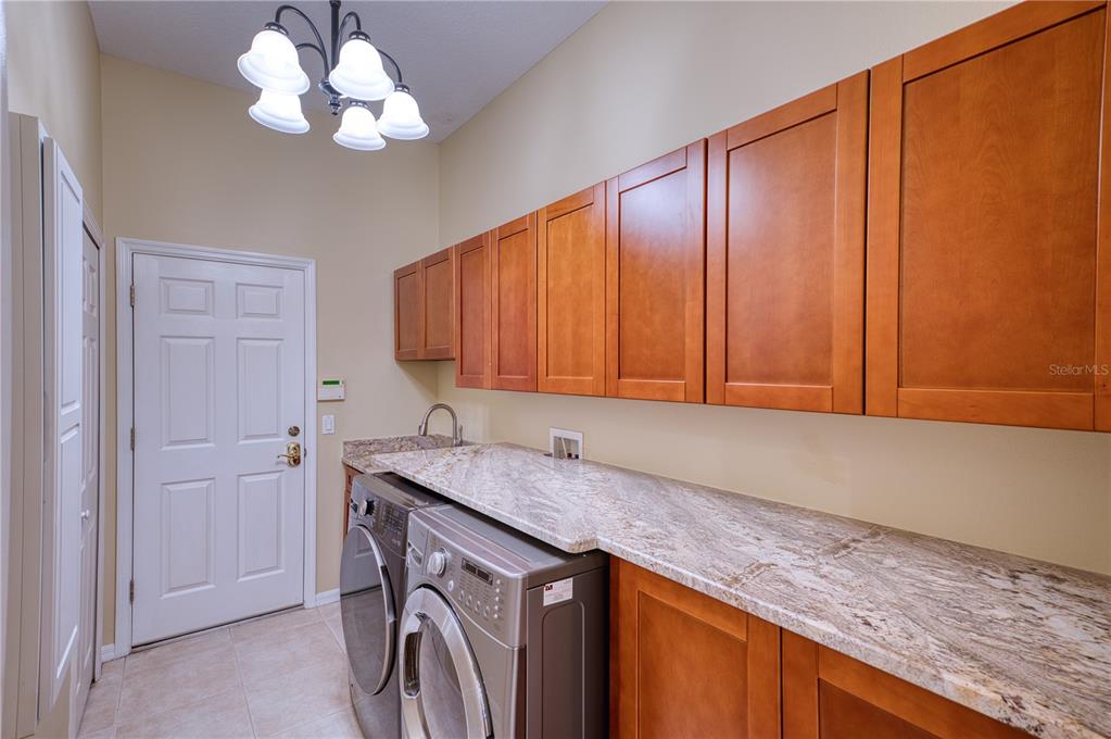 10523 Cheval Place Lakewood Ranch, FL 34202 - Photo 19 of 52 a kitchen with a sink a cabinetry and chandelier