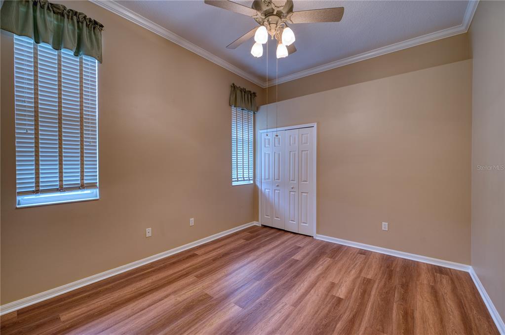 10523 Cheval Place Lakewood Ranch, FL 34202 - Photo 29 of 52 an empty room with wooden floor chandelier fan and windows