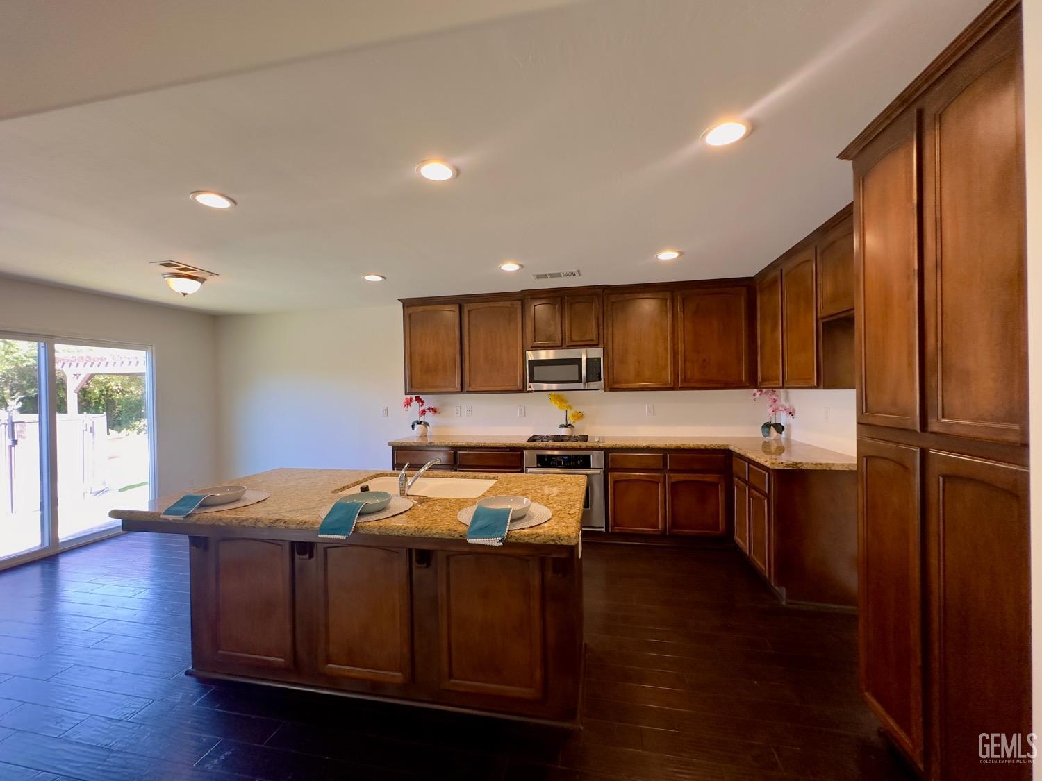 Undisclosed Address Bakersfield, CA 93311 - Photo 5 of 48 a large kitchen with stainless steel appliances wooden floors wooden cabinets a refrigerator and a sink