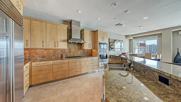 a hall with kitchen island granite countertop a large window and white cabinets