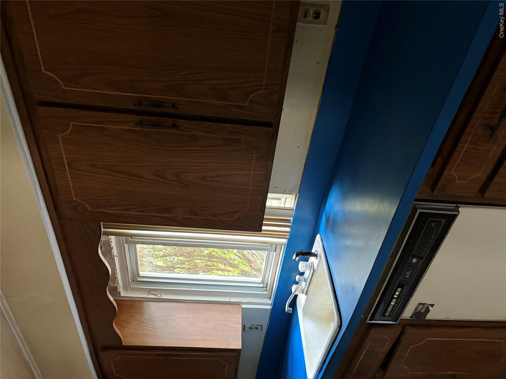 182 East Rockaway Road Hewlett, NY 11557 - Photo 6 of 8 Kitchen area featuring wood-finish cabinetry, a blue countertop, a white drop-in sink with a chrome faucet, and an integrated dishwasher