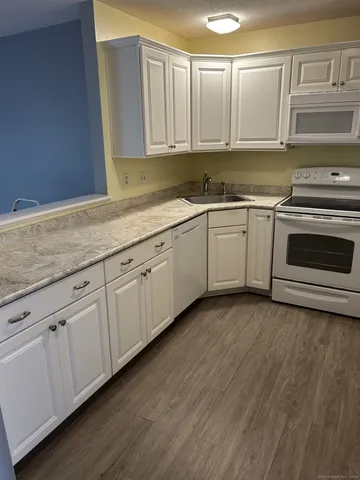 a kitchen with granite countertop white cabinets and white appliances