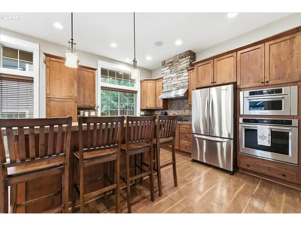 a kitchen with stainless steel appliances kitchen island granite countertop a refrigerator a stove a sink dishwasher with a dining table and chairs
