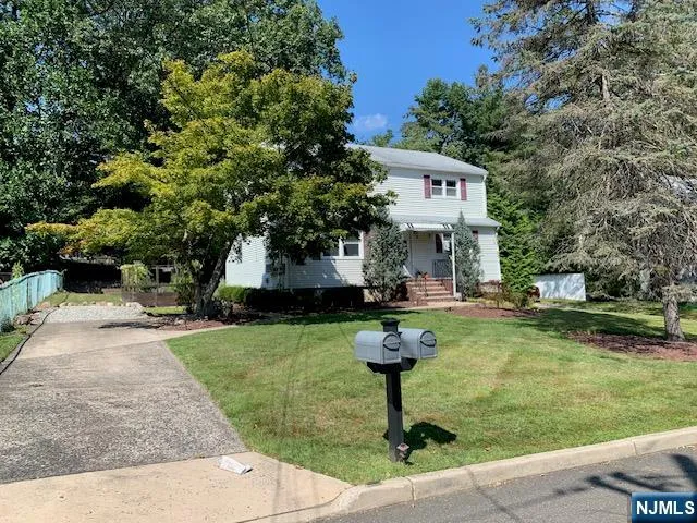 a front view of a house with garden and trees