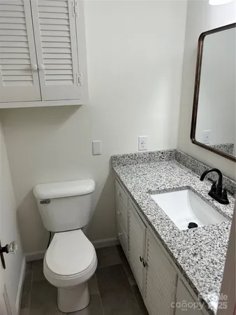 a bathroom with a granite countertop toilet sink and mirror