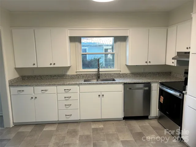 a kitchen with granite countertop white cabinets and stainless steel appliances