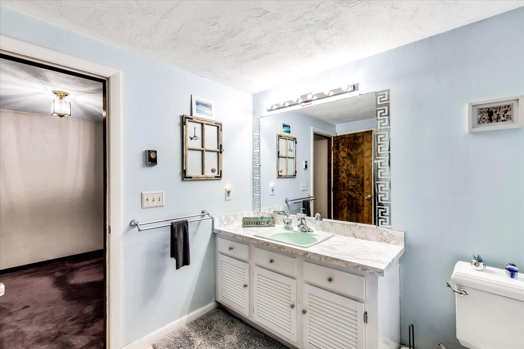 1007 River Road Marstons Mills, MA 02648 - Photo 26 of 33 a bathroom with a granite countertop sink vanity mirror and toilet