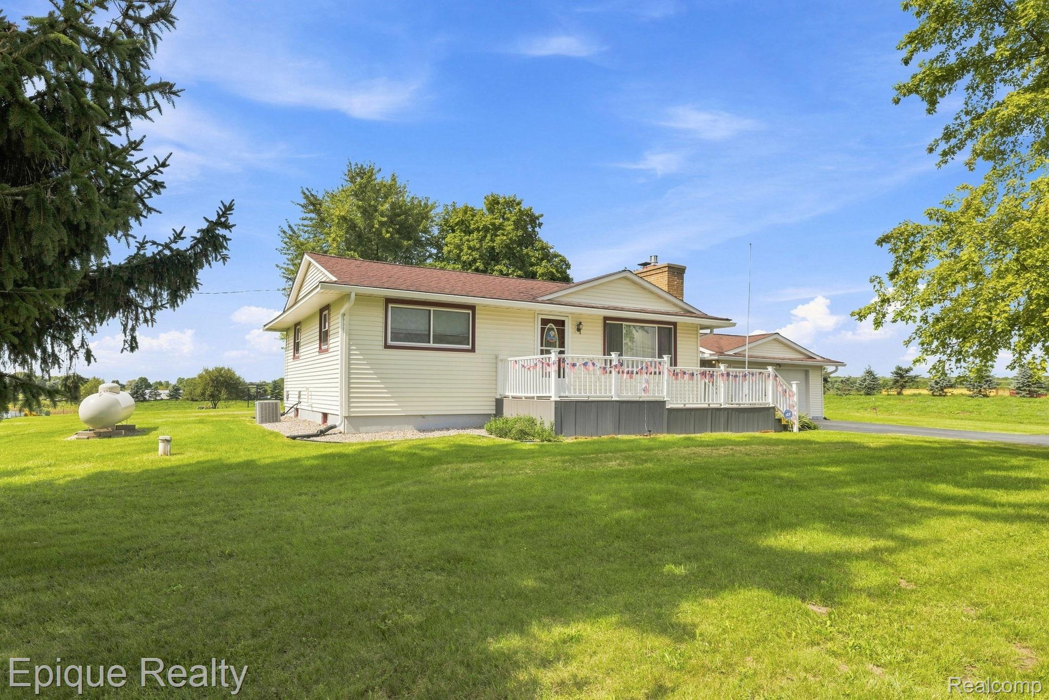 10091 North Genesee Road Mount Morris, MI 48458 - Photo 33 of 35 Expansive green lawn surrounds a siding-clad residence with a wide deck, attached garage, and visible propane tank