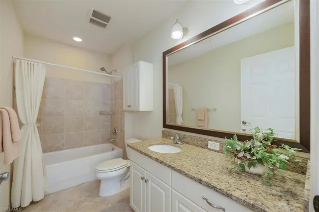 a bathroom with a granite countertop sink a toilet a mirror and shower