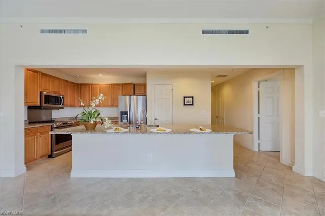 a view with kitchen island a sink a counter top space and stainless steel appliances