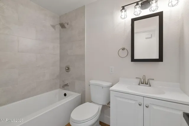 a bathroom with a toilet sink vanity tub and mirror