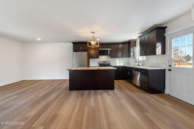 a large kitchen with kitchen island a sink dishwasher a stove and a refrigerator with wooden floor