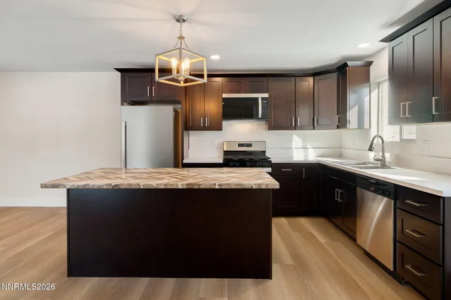 a kitchen with kitchen island stainless steel appliances a sink stove and refrigerator