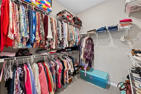 a view of walk in closet with clothes and shoes