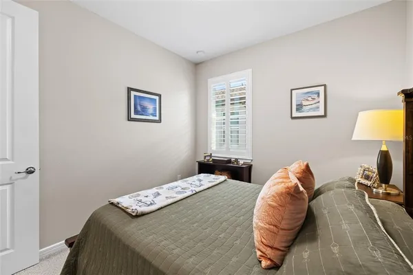 a bedroom with a bed and a lamp on dresser