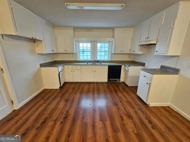 a kitchen with wooden floors and white appliances