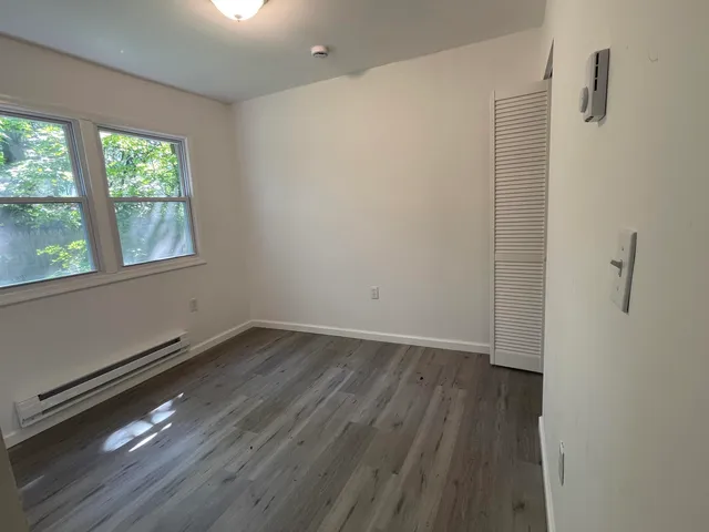 an empty room with wooden floor and windows