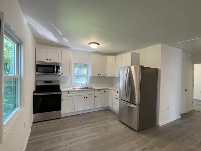 a kitchen with granite countertop a refrigerator stove and wooden floor