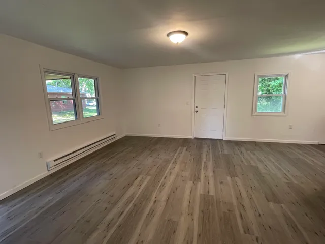 an empty room with wooden floor and windows