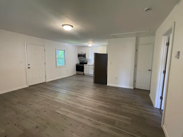 a view of empty room with wooden floor and window