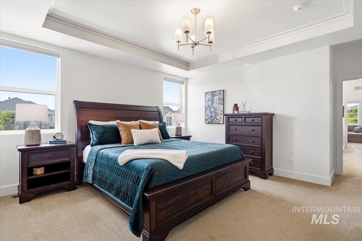 3794 South Single Tree Avenue Boise, ID 83716 - Photo 27 of 50 Spacious bedroom featuring multiple windows, a tray ceiling with crown molding, and a chandelier