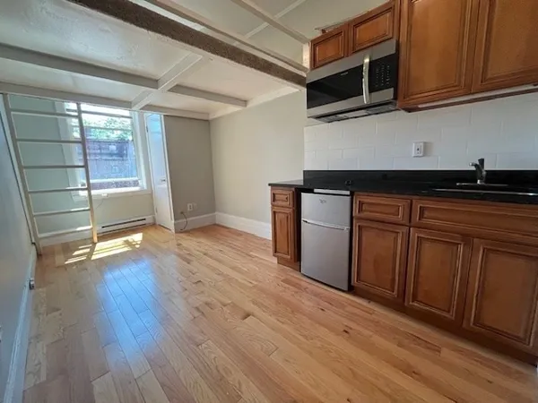 a kitchen with stainless steel appliances granite countertop a stove a microwave oven cabinets and wooden floor