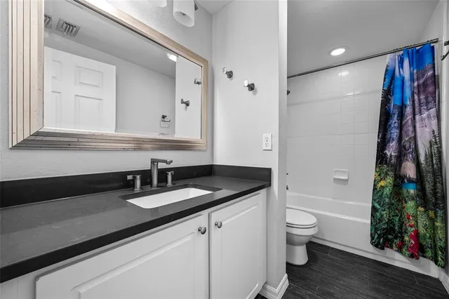 a bathroom with a granite countertop sink a toilet a mirror and shower