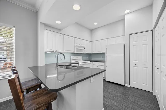a kitchen with stainless steel appliances granite countertop a table chairs in it and wooden floors