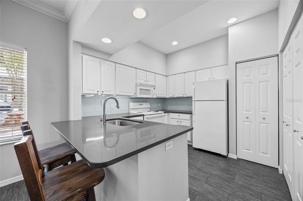 5141 Southwest 91st Way, Unit I102 Gainesville, FL 32608 - Photo 7 of 25 a kitchen with stainless steel appliances granite countertop a table chairs in it and wooden floors