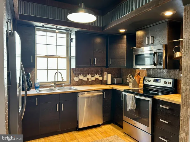 a kitchen with stainless steel appliances granite countertop a sink a stove cabinets and a microwave