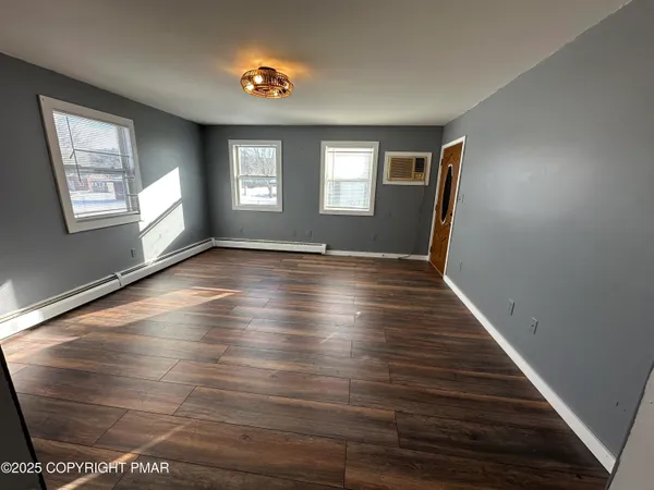 a view of an empty room with wooden floor and a window
