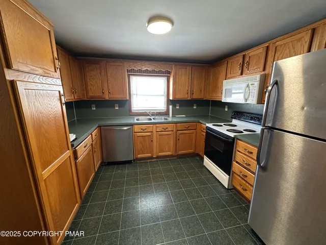 a kitchen with stainless steel appliances granite countertop a refrigerator a sink a stove a washer dryer and a refrigerator