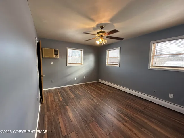 a view of an empty room with window and wooden floor