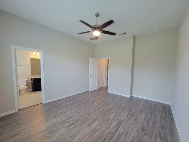 an empty room with wooden floor ceiling fan and window