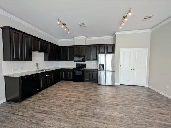 a large kitchen with stainless steel appliances granite countertop a large counter top a sink and a refrigerator