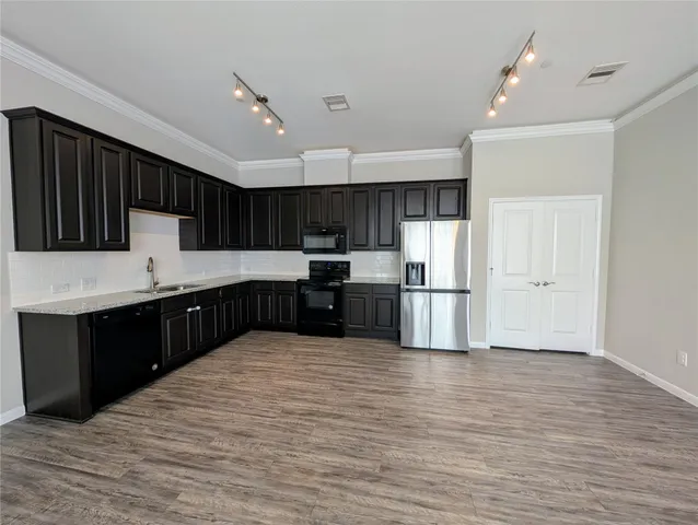 a large kitchen with stainless steel appliances granite countertop a large counter top a sink and a refrigerator