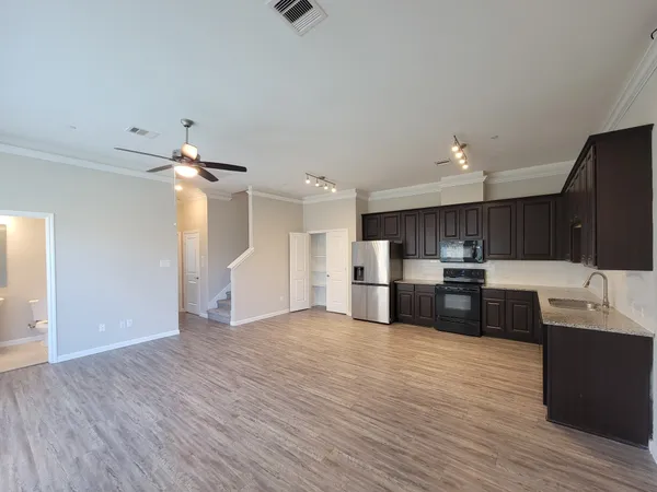 a kitchen with stainless steel appliances kitchen island wooden floors and white cabinets