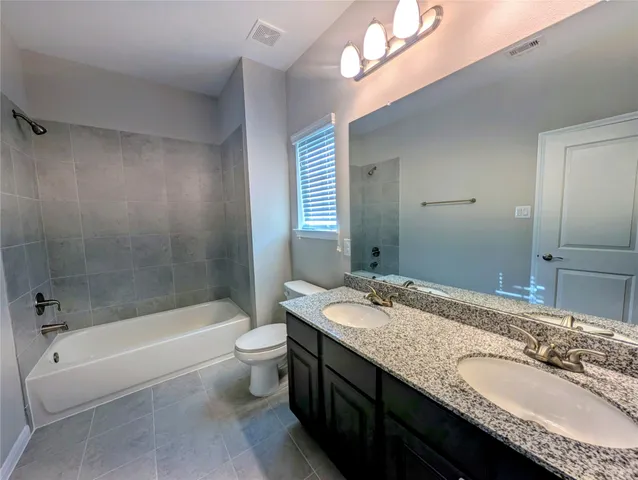 a bathroom with a granite countertop tub a double vanity sink and a mirror