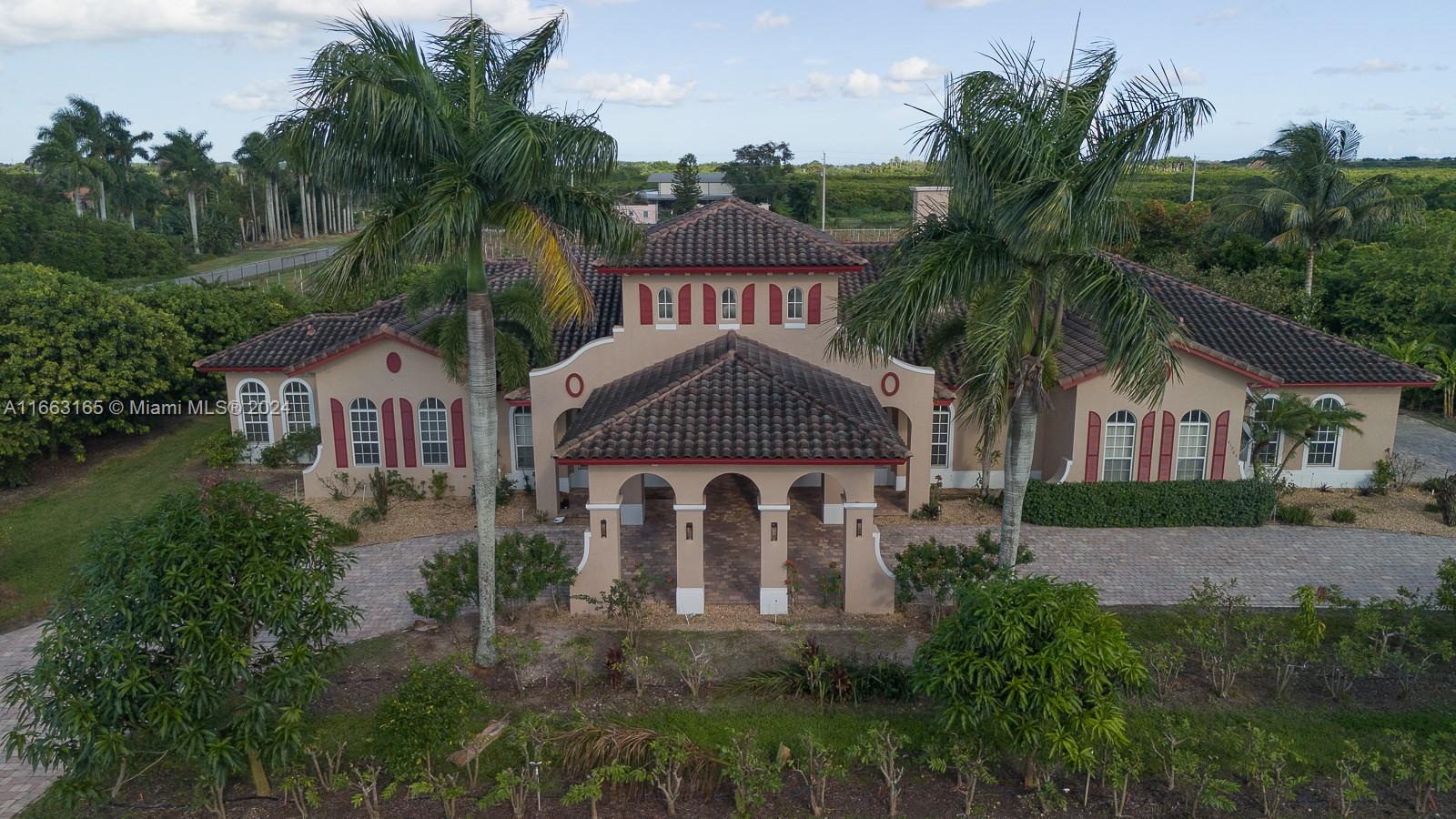 a front view of a house with a yard and palm trees