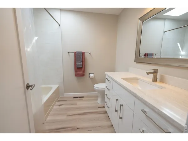 a spacious bathroom with a granite countertop sink a toilet a mirror and shower