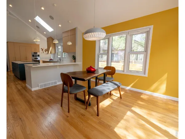 a living room with dining table wooden floor and a large window