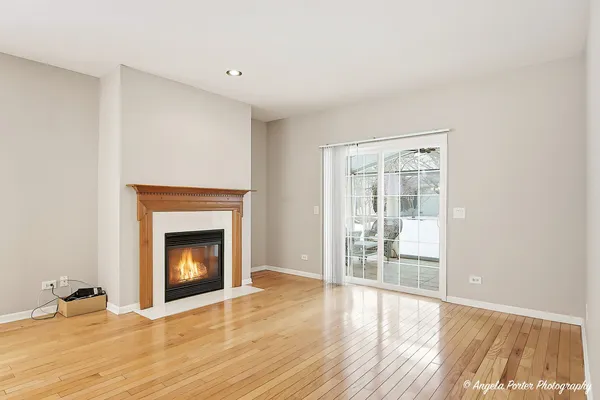 a view of an empty room with wooden floor fireplace and a window
