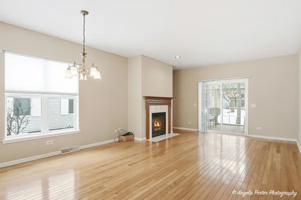 a view of a room with wooden floor fireplace and windows
