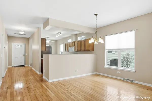 a view of a room with wooden floor a ceiling fan and windows