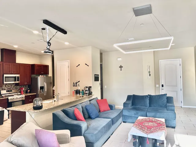 a living room with furniture kitchen view and a chandelier