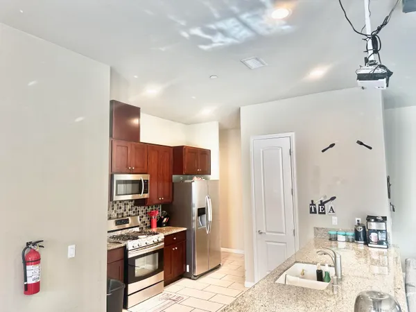 a kitchen with stainless steel appliances kitchen island granite countertop a sink cabinets and refrigerator