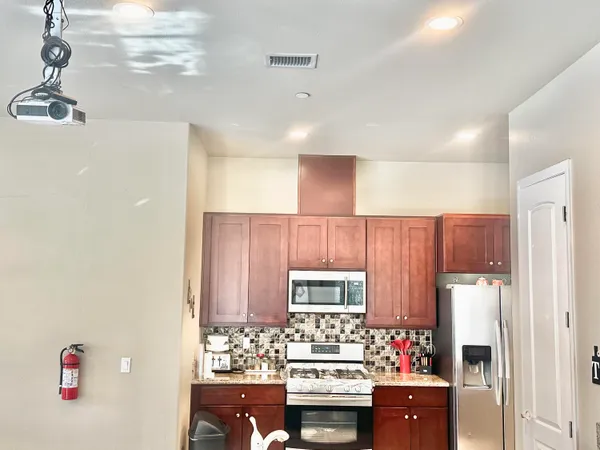 a kitchen with stainless steel appliances kitchen island granite countertop a refrigerator and a stove top oven