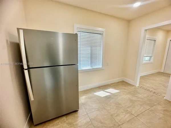 a view of a refrigerator in kitchen and an empty room