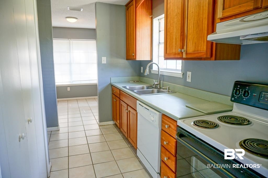 4366 Fathbrook Lane Mobile, AL 36693 - Photo 7 of 14 Kitchen with electric range, white dishwasher, a sink, under cabinet range hood, and light countertops