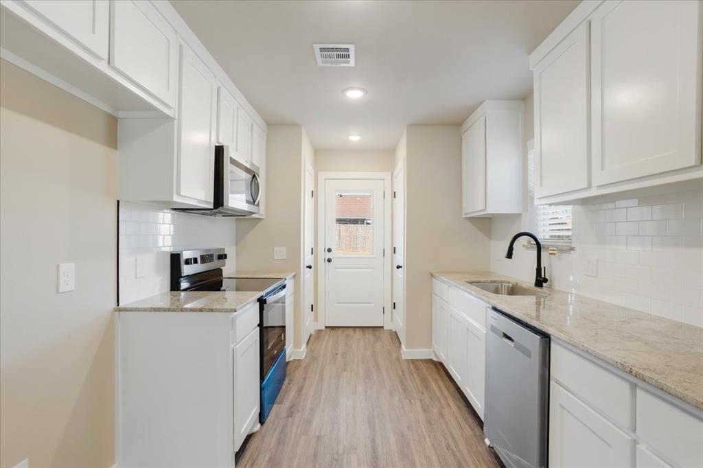 2385 Miller Street Denison, TX 75020 - Photo 11 of 26 a kitchen with stainless steel appliances a sink dishwasher a stove top oven a refrigerator with wooden floor and cabinets